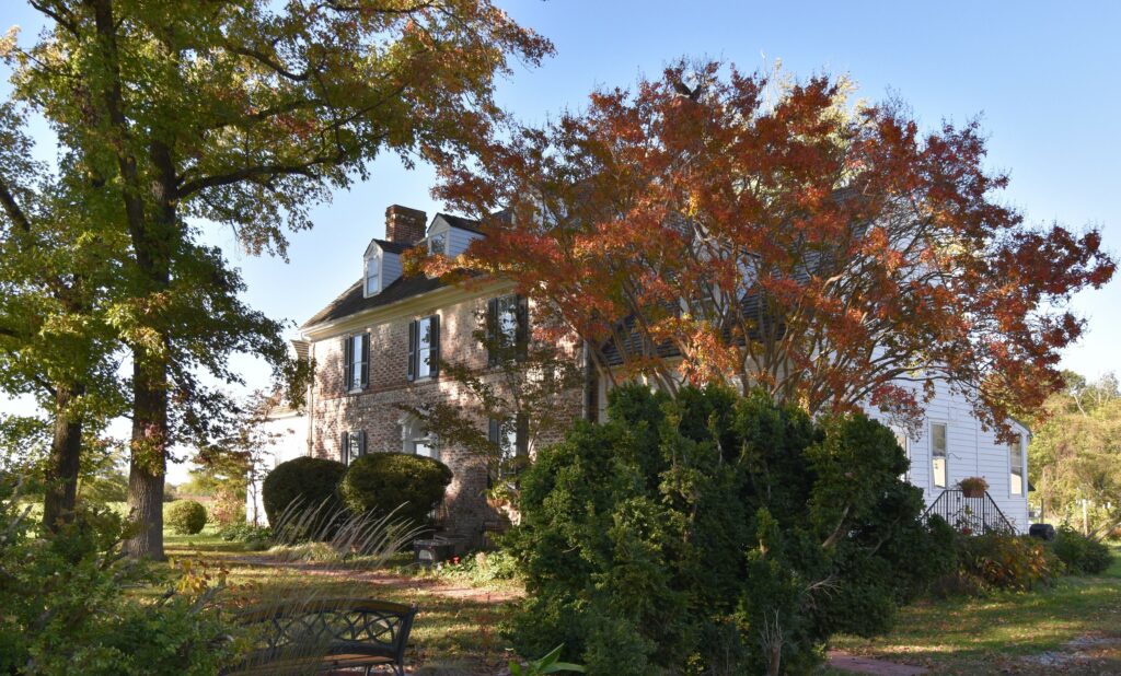 A traditional 1700s brick colonial home with Boxwoods, Crape Myrtle, and Sweet Gum Trees, where the Chesapeake Cottages roots began