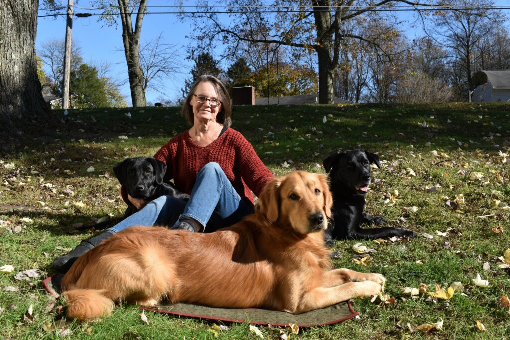 Elizabeth and the three pups under the trees at the home of Chesapeake Cottages LLC